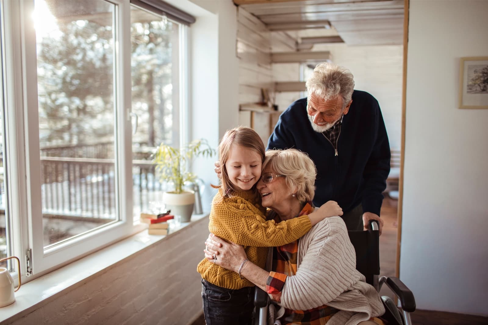 Multi-generation family. Senior woman in wheelchair hugging a young child in a home