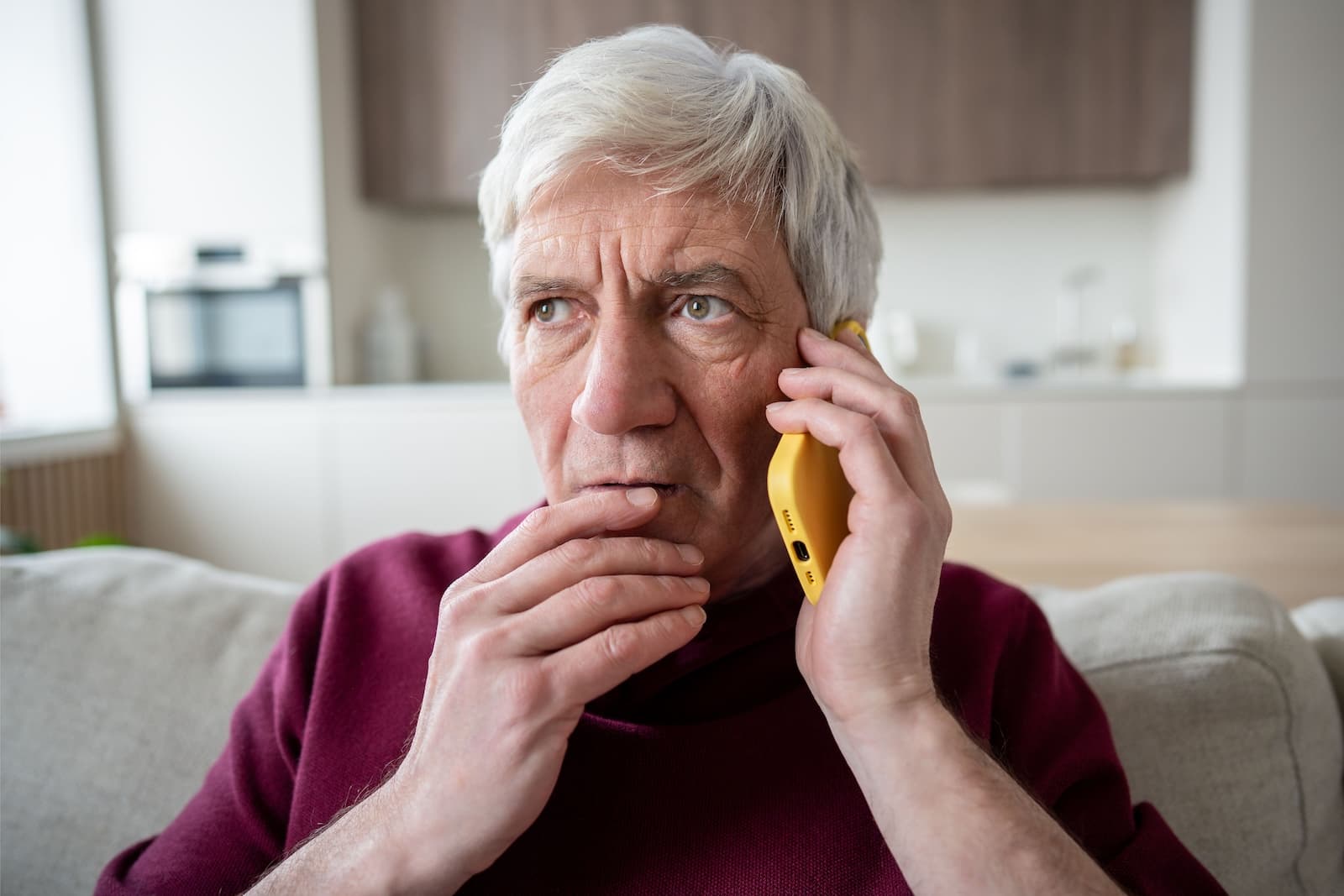 Suspicious elderly man with phone at home