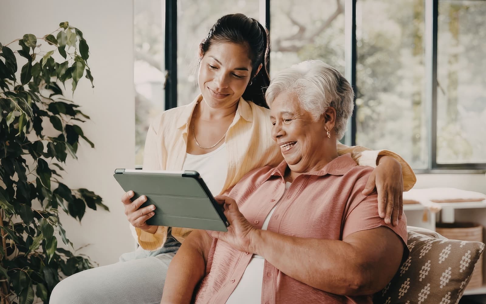 A woman helping a senior woman use a tablet