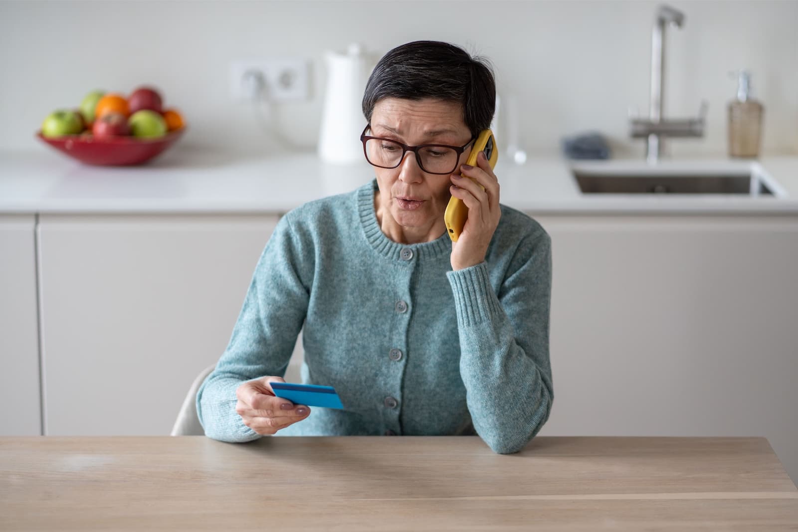 Concerned woman on phone with credit card on hand